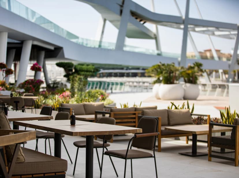 Rooftop terrace at Tazal Restaurant Abu Dhabi featuring outdoor seating, large white planters, and a modern steel-and-glass