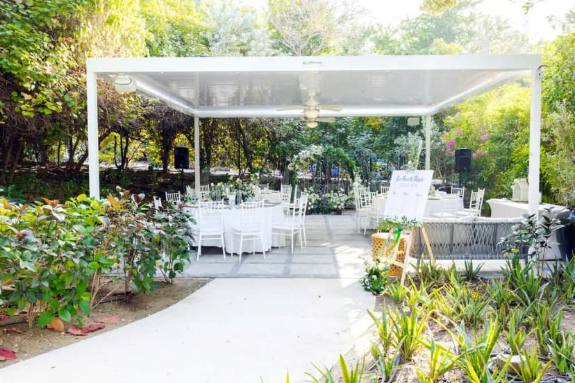 Terrace at The Farm Restaurant Al Barari in Dubai featuring a white pergola structure and lush green garden