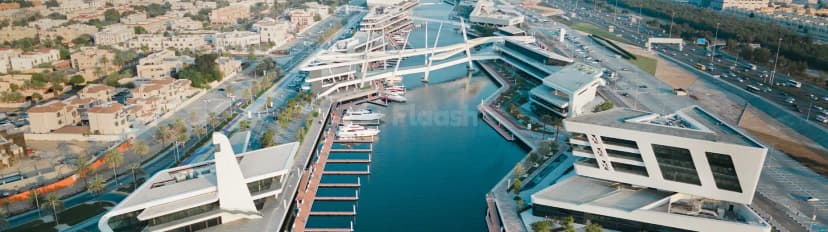 Al Qana facade in Abu Dhabi features modern white geometric architecture with large glass windows overlooking a marina