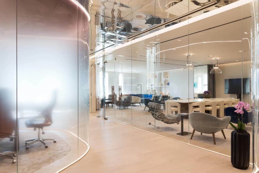 Meeting Room at Sanad Lounge Doha featuring a curved frosted glass partition and reflective ceiling with light wooden
