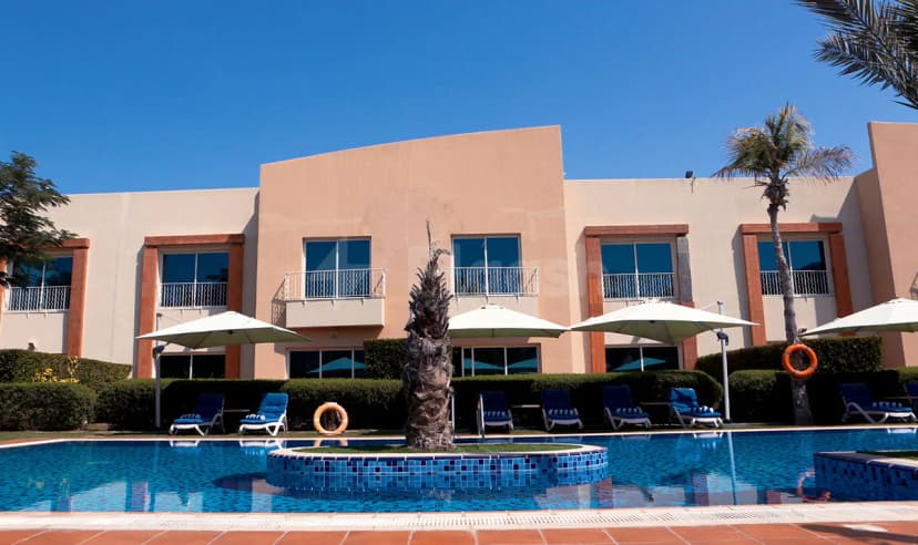 Rectangular swimming pool at Coral Boutique Villas in Dubai with blue mosaic tiles and a central palm tree