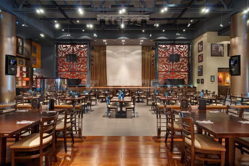 Restaurant interior at Hard Rock Cafe Dubai featuring a central stage with red patterned panels and hanging spotlights