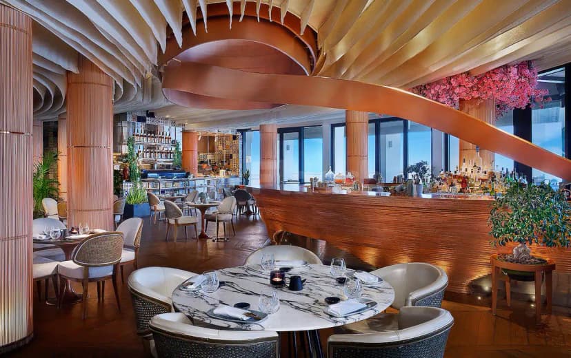 Restaurant interior at B Lounge Doha featuring a copper ceiling feature and bamboo-clad columns with a bar counter