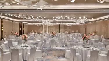 Ballroom at The St. Regis Riyadh featuring round tables with floral centerpieces and star-shaped ceiling decorations under ambient