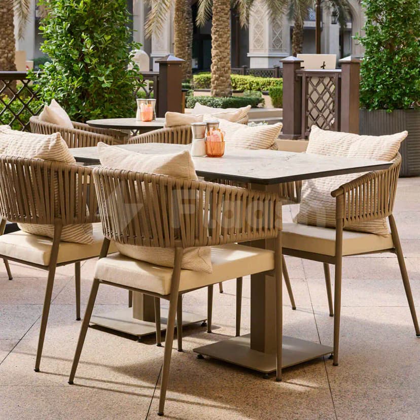 Terrace at Apricot Dubai Cafe Downtown Dubai featuring square marble-top tables, beige cushioned woven-back chairs, and potted greenery