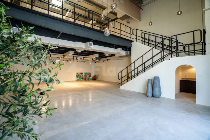 Ballroom at Slate The Space Dubai featuring a concrete floor, white walls, a black metal staircase, and hanging