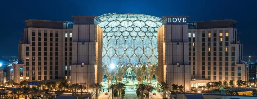 Hotel facade of Rove Expo 2020 in Dubai featuring an illuminated geometric glass dome and beige stone cladding