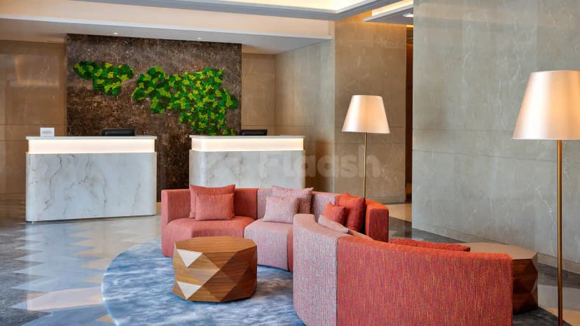 Entrance hall at Courtyard by Marriott Culture Village Dubai featuring a marble reception desk and green moss wall