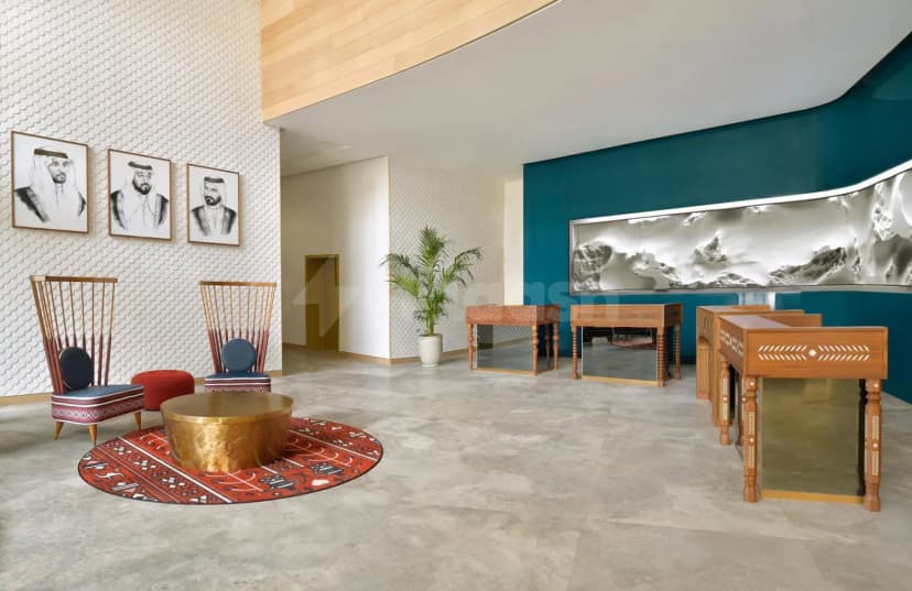 Entrance hall at Open Sesame Dubai featuring a textured white wall with portraits and a teal accent wall