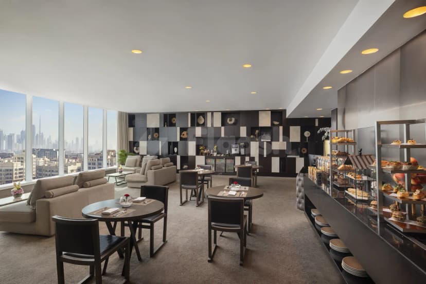 Restaurant interior at Signature by Sanjeev Kapoor Dubai featuring round wooden tables, black leather chairs, and floor-to-ceiling