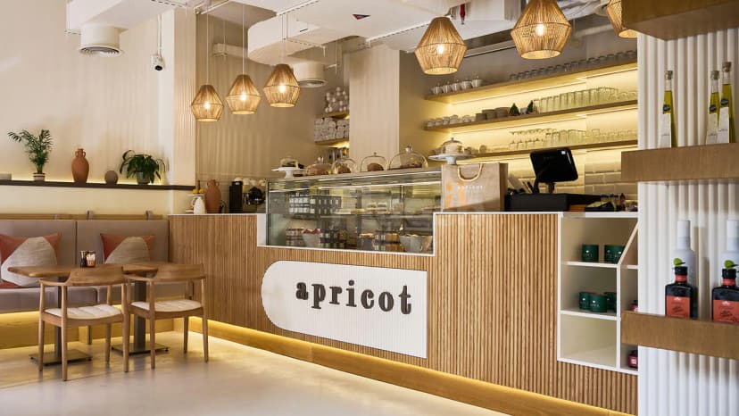 Apricot Dubai Cafe Downtown Dubai features a wooden counter with a glass pastry display and wicker pendant lighting