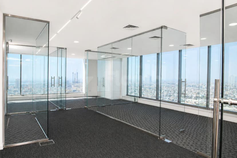 Meeting room at The H Hotel Dubai with glass partition walls and floor-to-ceiling windows offering a city