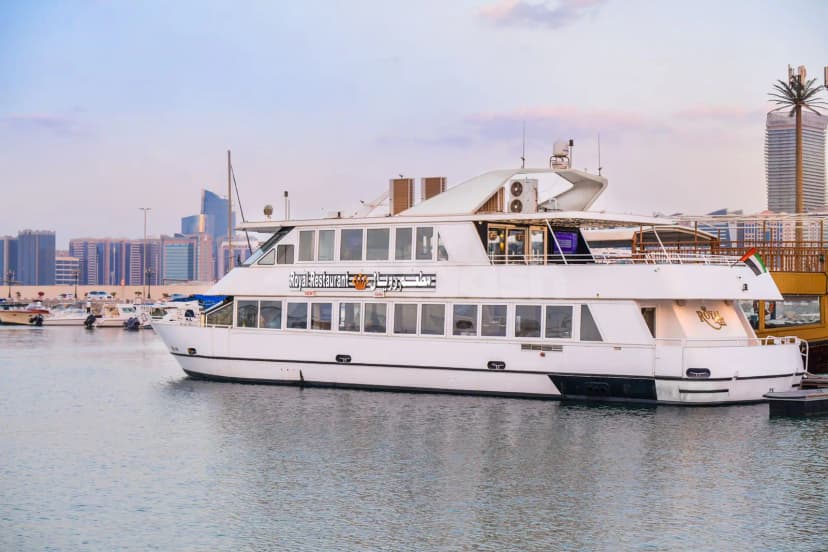 White multi-level Royal Yacht Restaurant vessel docked in Abu Dhabi marina with large windows and glass railing