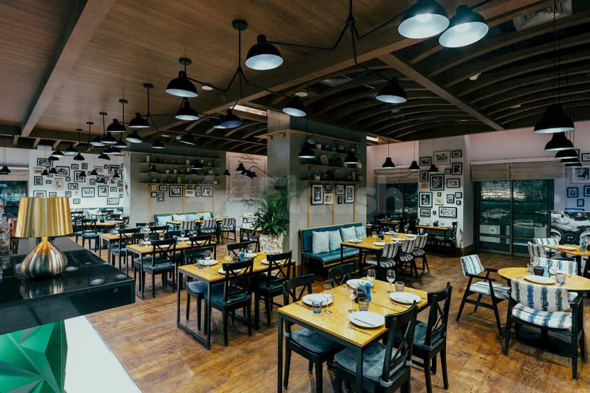 Restaurant interior at The Kitchen Doha featuring a wooden ceiling with exposed beams and black pendant lights