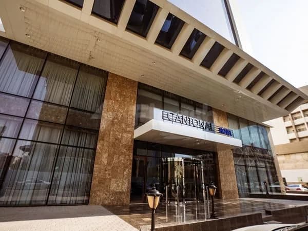 Hotel facade of Cantonal Hotel by Warwick in Riyadh featuring a glass entrance with revolving door, stone cladding