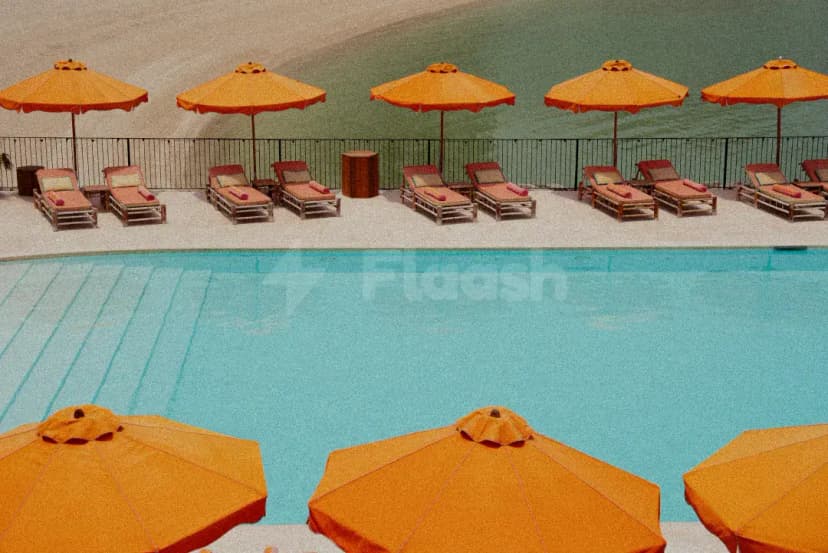 Rectangular swimming pool at Tagomago Dubai with turquoise water, orange umbrellas, and wooden lounge chairs on a light