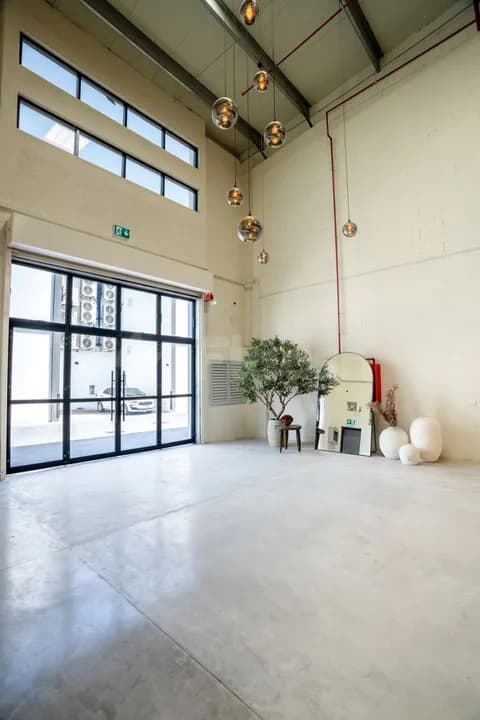 Entrance hall at Slate The Space Dubai featuring industrial ceiling with exposed beams, large glass doors, and hanging