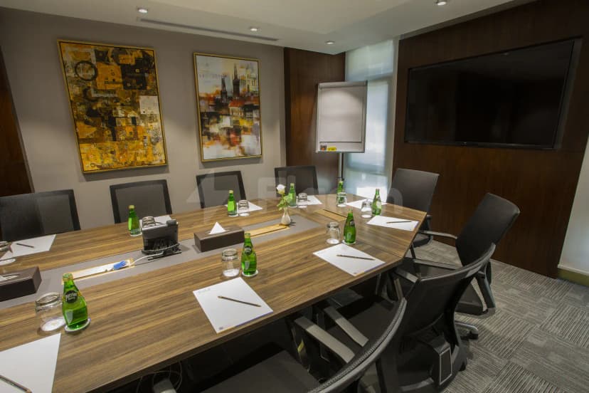 Boardroom at Velar Inn Hotel Taif with long wooden table, black mesh chairs, mounted TV, and two framed