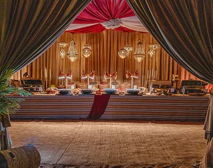 Ballroom at Nara Desert Escape in Dubai featuring a draped fabric entrance and hanging lanterns above a long