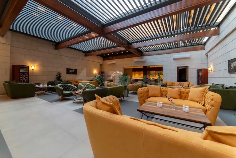 Entrance hall at Warwick Al Khobar featuring orange and green velvet lounge seating under a slatted metal roof