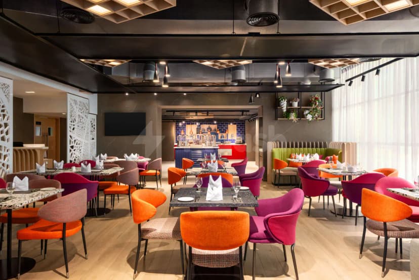 Restaurant at La Quinta by Wyndham Abu Dhabi Al Wahda featuring terrazzo tabletops, vibrant upholstered chairs
