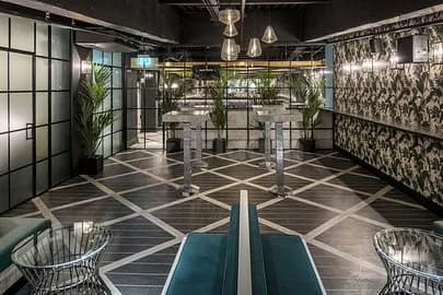 Restaurant interior at Swingers The Crazy Golf Club Dubai featuring a geometric patterned floor and floral wallpaper