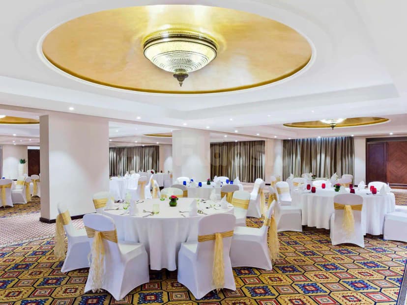 Ballroom at Al Liwan Restaurant Ras Al Khaimah with round tables, white chairs with gold sashes