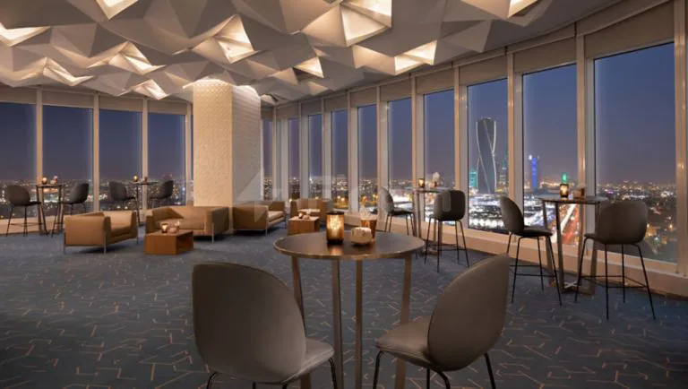 Rooftop terrace at Le Meridien Riyadh featuring geometric ceiling panels and floor-to-ceiling windows overlooking the city night