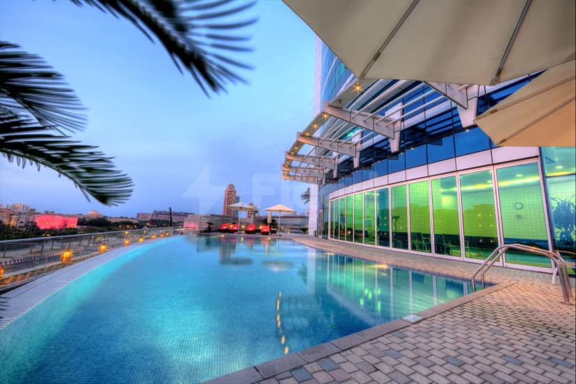 Rooftop swimming pool at Tamani Hotel Marina in Dubai with glass wall and city skyline view