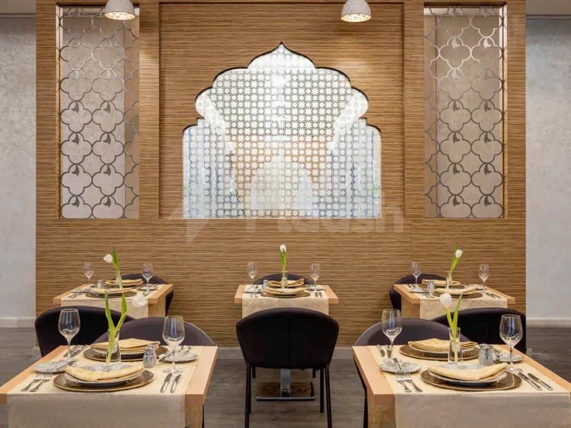Restaurant at Novotel Thakher Makkah featuring ornate geometric wall panels and a backlit arched decorative screen above set