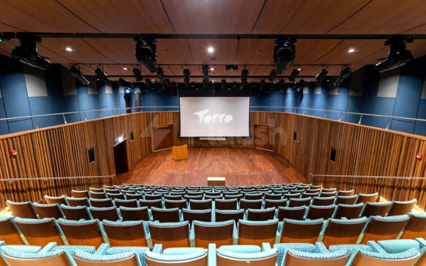 Auditorium at The Nexus, Expo City Dubai, featuring tiered seating, a wooden stage, and a large projection screen