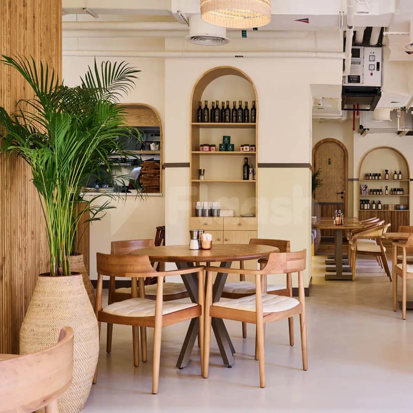 Round wooden table area at Apricot Dubai Cafe Downtown Dubai with tall palm plant in woven vase