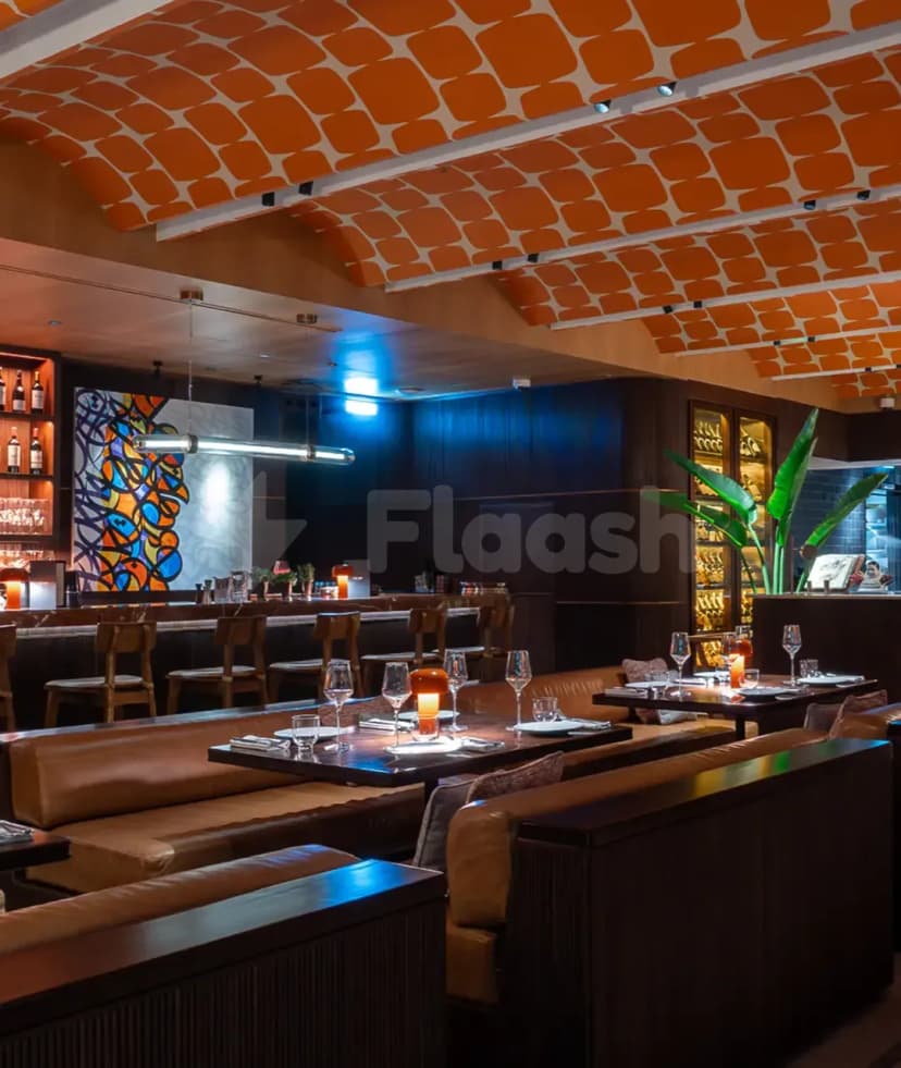 Restaurant interior at Chez Wam in Dubai featuring an orange patterned ceiling and dark wooden walls with leather