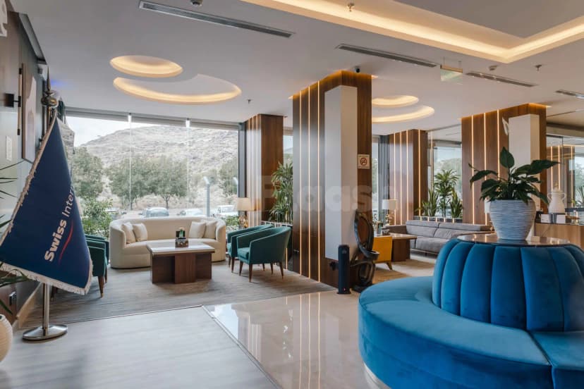 Entrance hall of Swiss International Taif in Taif featuring a blue velvet curved sofa and large glass windows