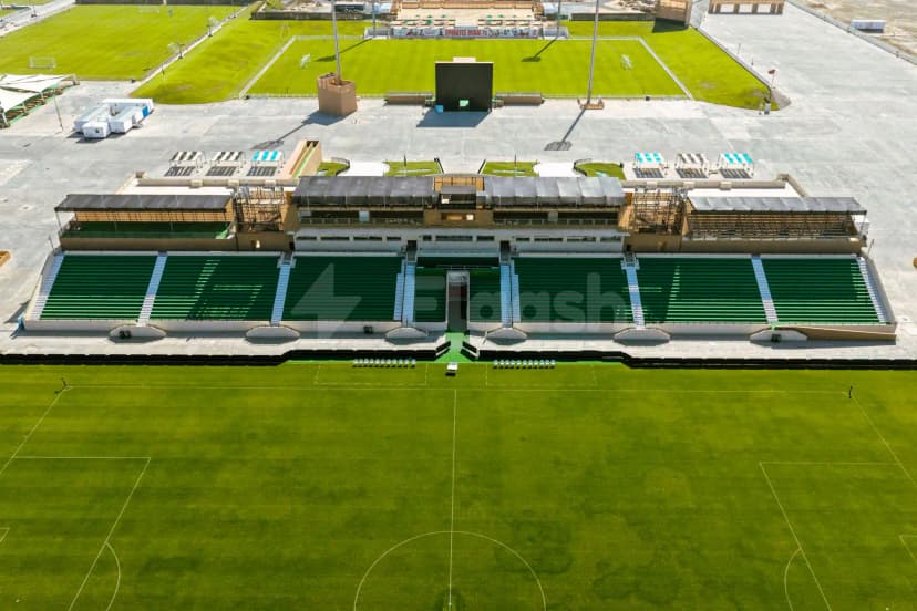 The Sevens Stadium in Dubai features a green artificial turf field with white markings and covered green seating