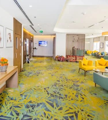 Entrance hall at Mena Plaza Hotel Albarsha in Dubai featuring a yellow and blue patterned carpet and wooden