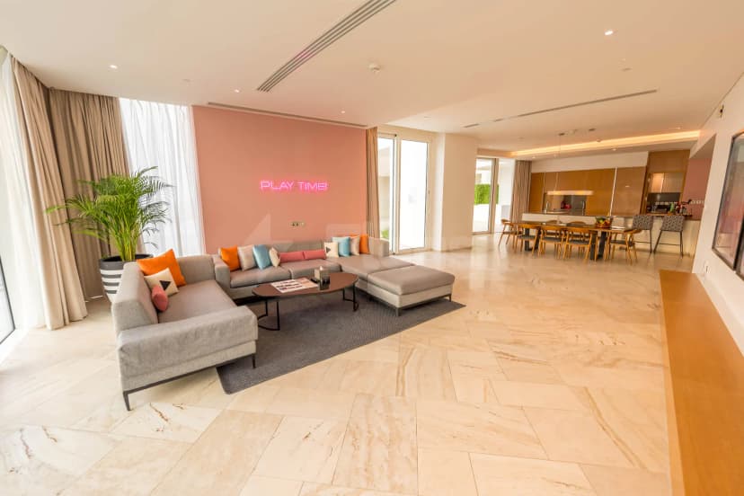 Grey sectional sofa in Five Jumeirah Village Dubai meeting room with pink wall and neon 'PLAY TIME' sign