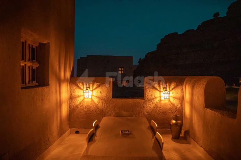Rooftop terrace at Suhail Arabic Restaurant Riyadh featuring stone walls, wall-mounted lanterns, and a rectangular dining table under