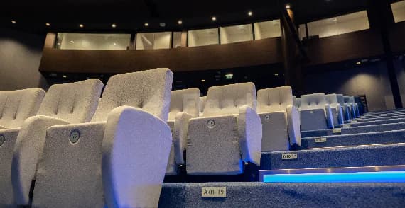 Theatre-style seating at Jafza One Convention Centre in Dubai, featuring tiered rows, white upholstered chairs, and blue LED