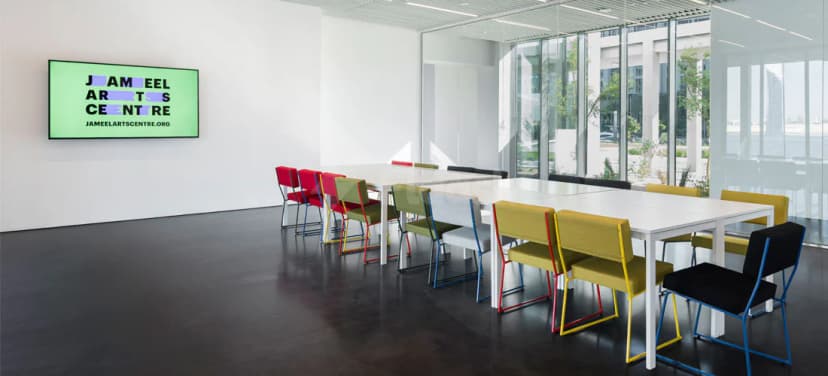 Meeting room at Jameel Arts Centre in Dubai with long white table and vibrant modular chairs