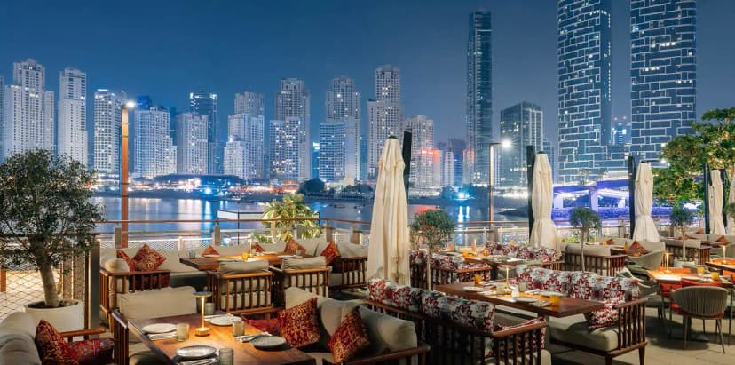Rooftop terrace at Grand Zor Restaurant Dubai with cushioned benches, patterned upholstery, and a view of illuminated skyscrapers