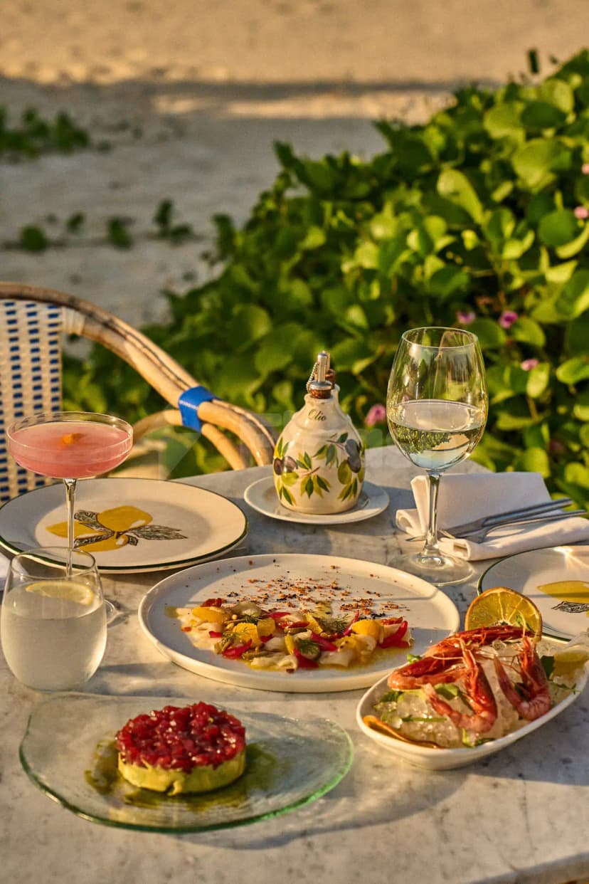 Outdoor dining setup at Lucia's Mare Restaurant Dubai featuring a marble table with seafood dishes and green leafy