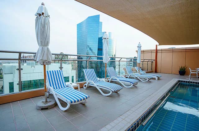 Rooftop terrace at Sheraton Khalidiya in Abu Dhabi with rectangular blue-tiled pool and city skyline view