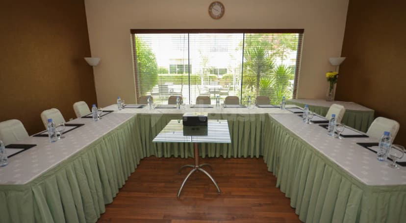 Meeting room at Coral Boutique Villas Dubai with U-shaped table layout, central projector on glass pedestal, and large