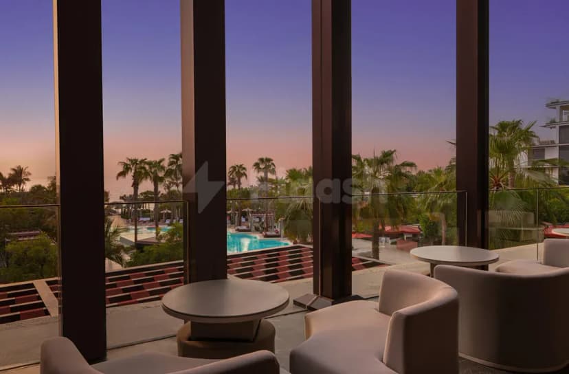 Rooftop terrace at TakaHisa Restaurant Dubai featuring beige armchairs, round tables, glass railing, and a pool view