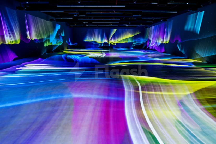 Ballroom at SEE Institute Dubai featuring immersive aurora borealis light projections on dark walls and a reflective floor