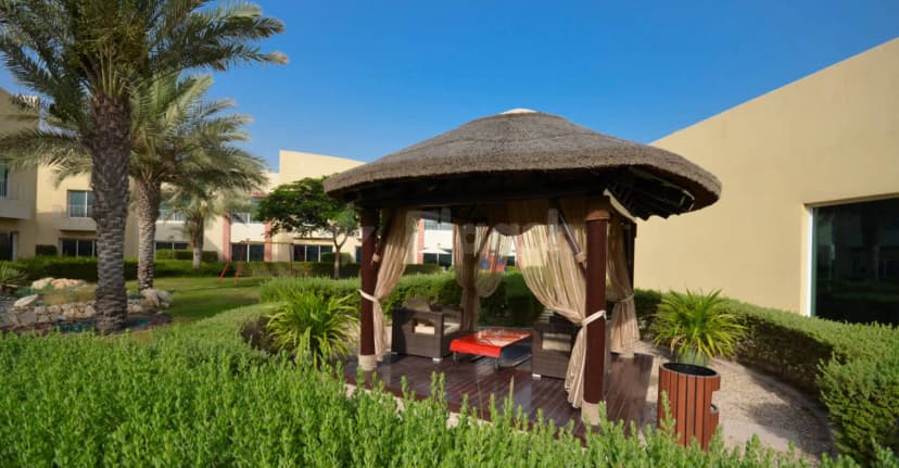 Thatched roof gazebo on a wooden deck at Coral Boutique Villas in Dubai, surrounded by palm trees