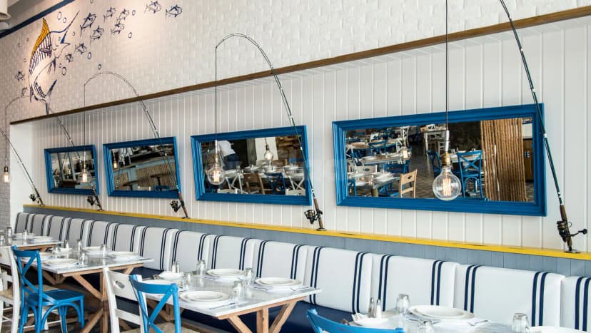 Ibn AlBahr Seafood Restaurant in Dubai features a nautical-themed dining space with blue-framed mirrors and fishing rod decor