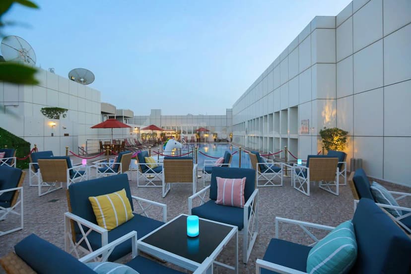 Rooftop terrace at Ivory Grand Hotel Apartments Dubai featuring an outdoor pool, blue lounge chairs, and warm ambient