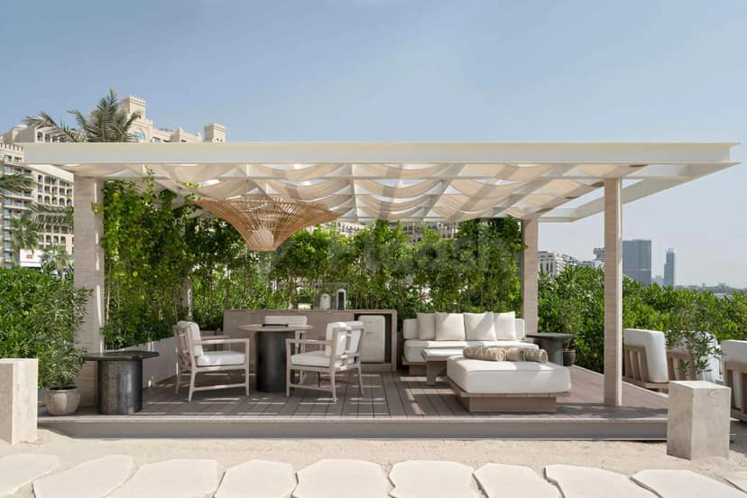 Rooftop terrace at San Beach Dubai featuring a white canopy over a wooden deck with green climbing plants